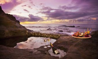 a romantic dinner on the beach with two wine glasses and a bottle of wine placed on a stone at Cap Maison Resort & Spa