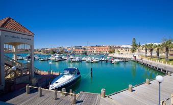 a marina with multiple boats docked in the water , creating a picturesque scene against a clear blue sky at The Marina Hotel - Mindarie