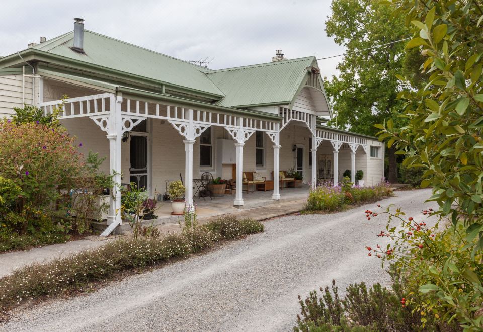 a large white house with a green roof and white columns is surrounded by greenery at Yarra Gables