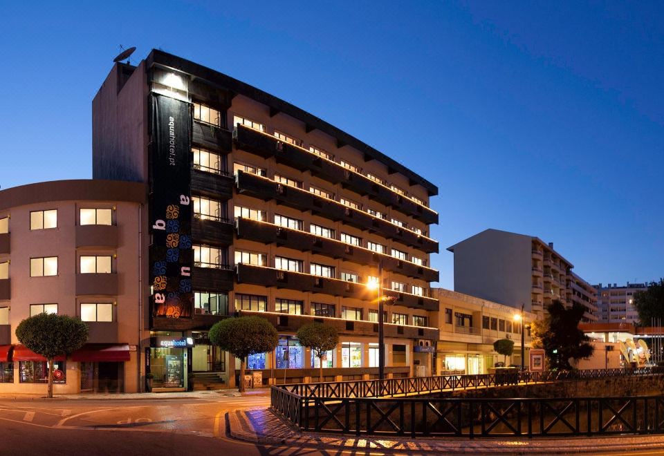 a city street with a tall apartment building on the left side of the street , illuminated at night at AquaHotel