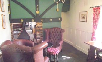 a cozy living room with green walls , two leather couches , and a dining table in the background at The Exeter Inn