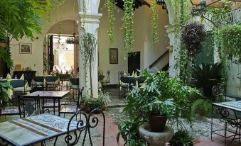 a courtyard with tables and chairs surrounded by potted plants , creating a relaxing atmosphere for outdoor dining at Hostal Valencia