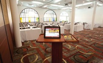 a conference room with a tablet on a podium , surrounded by chairs and tables , arranged in an open space at Hotel Union
