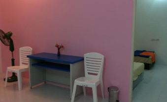 a pink room with a desk , chairs , and a fan , as well as a bed in the background at V at Panus