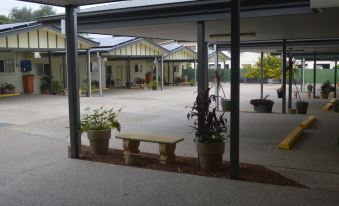 a bench is sitting in the middle of a covered area with potted plants and houses visible outside at Best Western Caboolture Gateway Motel