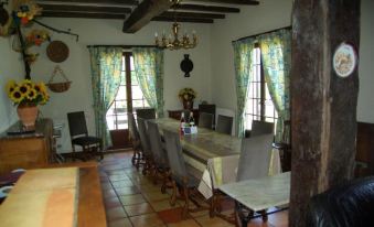 a dining room with a large wooden table surrounded by chairs , and a chandelier hanging from the ceiling at L'Horizon