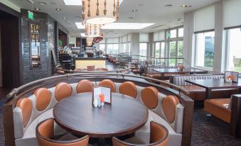 a dining room with a round table surrounded by chairs and a chandelier hanging from the ceiling at Seamill Hydro Hotel