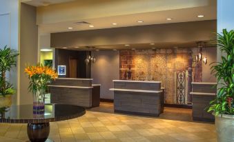 a modern hotel lobby with wooden reception desks , floral arrangements , and a large mural on the wall at Winston-Salem Marriott