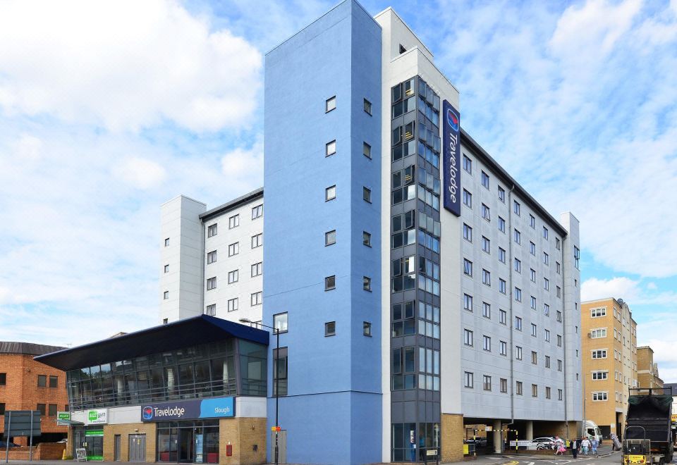"a modern blue and white building with the name "" express "" on it , surrounded by other buildings and cars on the street" at Travelodge Slough