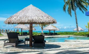 a luxurious beach resort with umbrellas , chairs , and tables set up around a pool , offering a relaxing atmosphere for guests at Coconuts Beach Club Resort and Spa