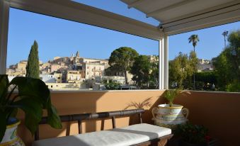 a balcony with a wooden bench and a view of a city in the background at Hotel Flora