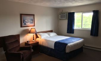 a hotel room with a comfortable bed , a chair , and a window with curtains at Fairway Inn