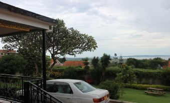 a white car is parked in a driveway near a house with a view of the ocean at Lake Victoria View Guesthouse