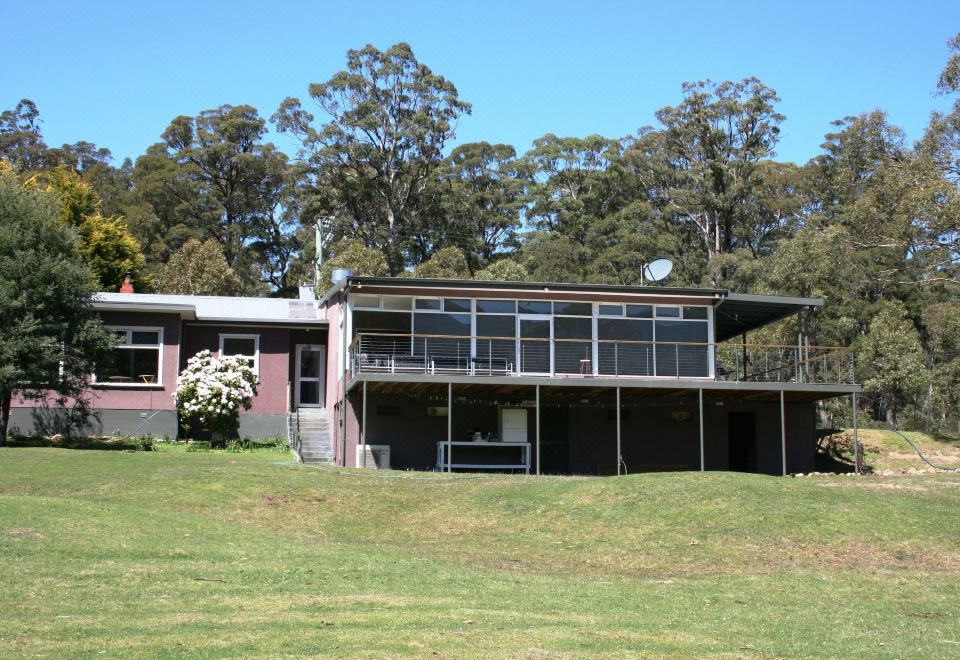a modern house with a red roof and large windows , situated on a grassy field surrounded by trees at Craggy Peaks