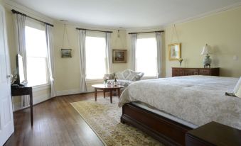 a spacious bedroom with hardwood floors , a large bed , and a chair in the corner at Woodville Bed and Breakfast