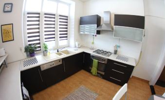 a clean and well - organized kitchen with black cabinets , stainless steel appliances , and a dining table at Downtown Apartments