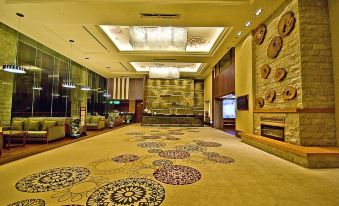 a large hotel lobby with a carpeted floor and a fireplace in the background , creating a warm and inviting atmosphere at Alishan House