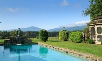 a large swimming pool surrounded by a grassy area , with mountains in the background , under a clear blue sky at Glen Gordon Manor