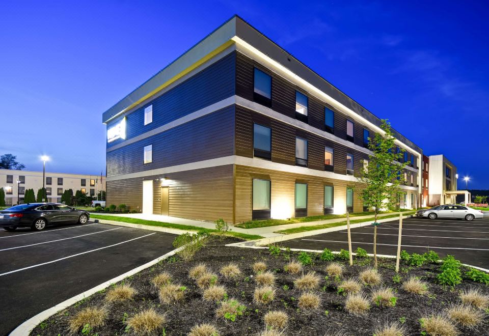 a modern building with wooden siding and large windows , surrounded by plants and gravel , under a clear blue sky at Home2 Suites by Hilton Mechanicsburg