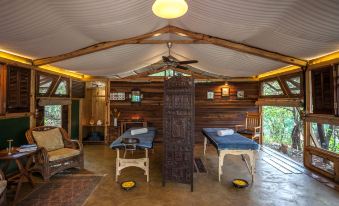 a wooden room with two massage tables , one on the left and one on the right , surrounded by chairs at The Machan