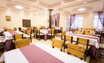 a large dining room with multiple tables and chairs , some of which are covered with white tablecloths at Well Hotel