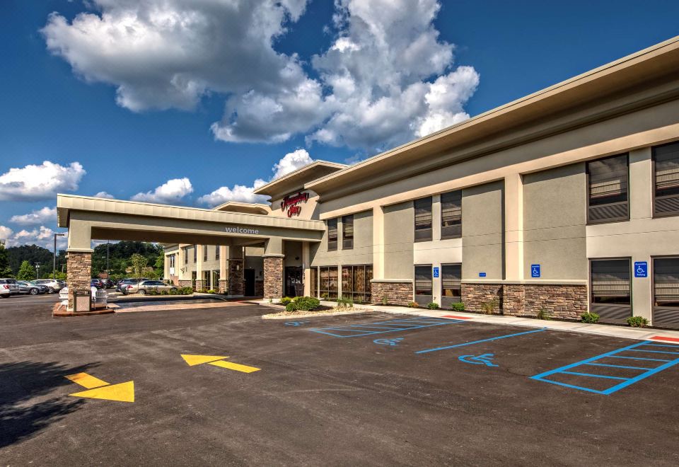 a large building with a covered walkway and a parking lot in front of it at Hampton Inn Ashland