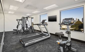 a well - equipped gym with various exercise equipment , including treadmills and weight machines , in a spacious room with large windows at Quest Kings Park