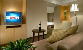 The room is equipped with a couch, chair, and table positioned in front of a wall-mounted TV at City Suites (Taoyuan Gateway)
