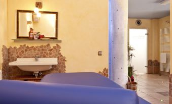 a massage room with a blue couch and a white sink , creating a spa - like atmosphere at Hotel am Kurpark