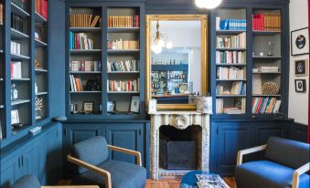 a living room with blue walls , bookshelves filled with books , and a fireplace in the center at Hotel Spa Azteca Barcelonnette