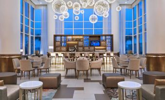 a large , modern room with multiple seating arrangements and a bar area , decorated with unique lighting and chandeliers at Guyana Marriott Hotel Georgetown