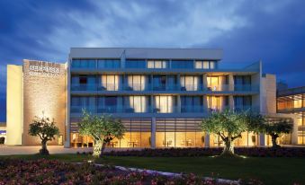 a large building with multiple floors and balconies is lit up at night , surrounded by trees and flowers at Kempinski Hotel Adriatic Istria Croatia