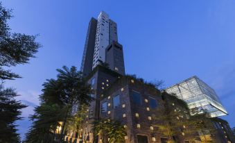 a tall building with many windows is surrounded by greenery and lit up at night at Alila Solo