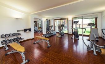 a well - equipped gym with various exercise equipment , including treadmills and weight machines , set up in a spacious room at Hotel Santa Gilla