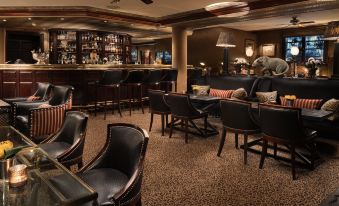 a bar area with several chairs and couches , as well as a television in the background at Hotel d'Angleterre