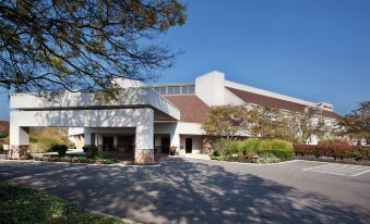 a large building with a parking lot in front of it , surrounded by trees and bushes at Doubletree by Hilton Columbus Dublin