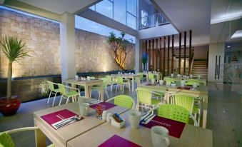 a modern restaurant with green tables and chairs , purple placemats , and a view of the city at favehotel Langko Mataram - Lombok