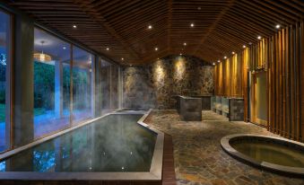 a large indoor pool surrounded by wooden walls , with a hot tub situated in the middle of the room at Alba Wellness Valley by Fusion