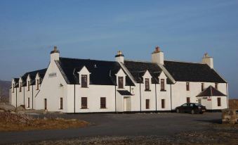 a large white building with black roofs and chimneys , standing in front of a clear blue sky at Polochar Inn
