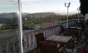 a balcony with wooden chairs and a dining table , offering a panoramic view of the countryside at Hotel Ría de Suances