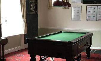 a pool table is set up in a room with a dartboard and a dartboard on the wall at The Old Pound Inn