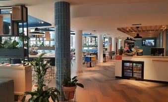 a modern , well - lit restaurant with various dining areas and a bar area , including a kitchen and bar area at Hampton by Hilton Antwerp Central Station