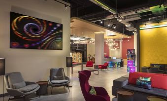 a modern lounge area with various seating options , including chairs and couches , in a well - lit room at Aloft Coral Gables