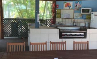 a dining area with wooden tables and chairs , as well as a kitchen with a refrigerator and sink at BIG4 Hervey Bay Holiday Park