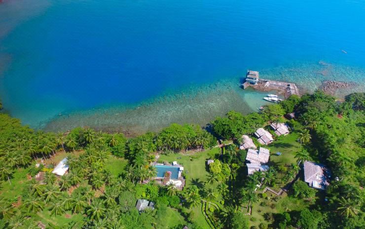 aerial view of a tropical island with a resort surrounded by lush greenery and a body of water at Janji Laut Resort