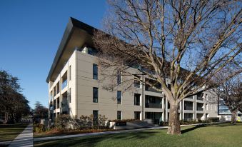 a modern building with a large tree in front of it and a clear blue sky above at Knightsbridge Canberra