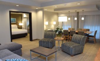 a hotel room with two beds , a dining table , chairs , and couches arranged in a living area at Holiday Inn Cincinnati N - West Chester