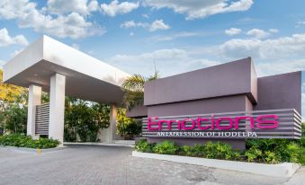 "a modern building with a large sign that says "" interloft "" in the front entrance , surrounded by palm trees and other greenery" at Emotions by Hodelpa - Juan Dolio
