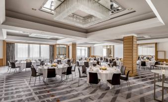 a large , well - lit banquet hall with multiple dining tables and chairs set up for a formal event at Stuttgart Marriott Hotel Sindelfingen