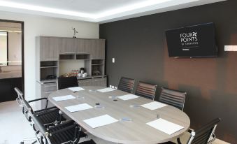 a conference room with a large table surrounded by chairs and papers , along with a tv mounted on the wall at Four Points by Sheraton Veracruz